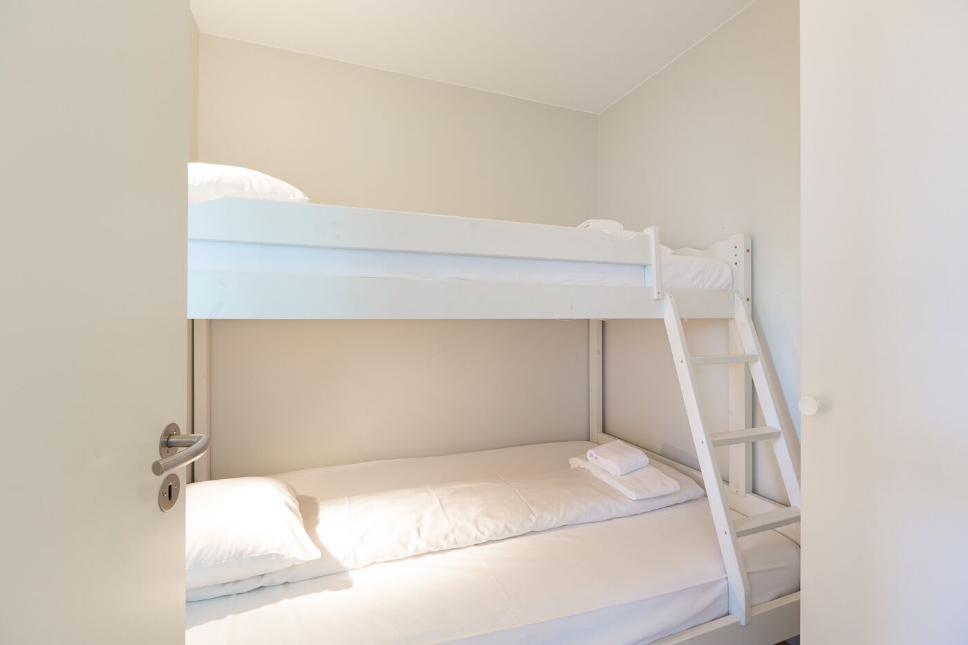 A bunk bed with white bedding and a ladder.