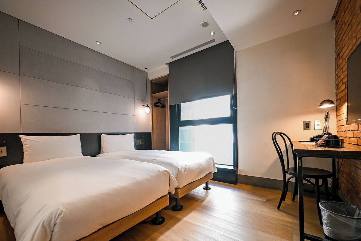 Una habitación de hotel moderna con una cama grande, un escritorio con una silla y una ventana que proporciona luz natural.