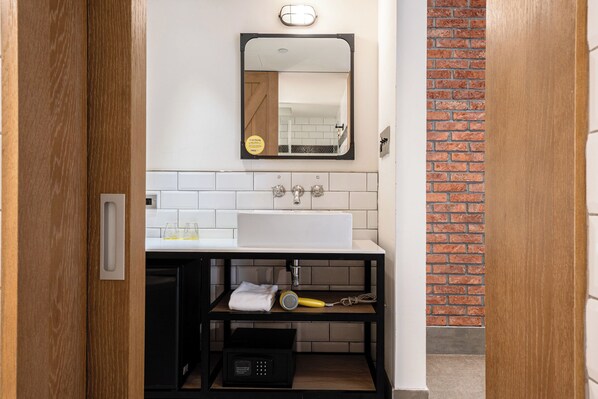 Un baño pequeño con un lavamanos blanco, un espejo y un mueble negro en la parte inferior.