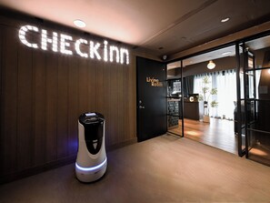 A hotel entrance with a 'CHECKIN' sign, a 'Living Room' sign, and a robot on the floor. - CHECK inn Taipei Songjiang (Taipei)