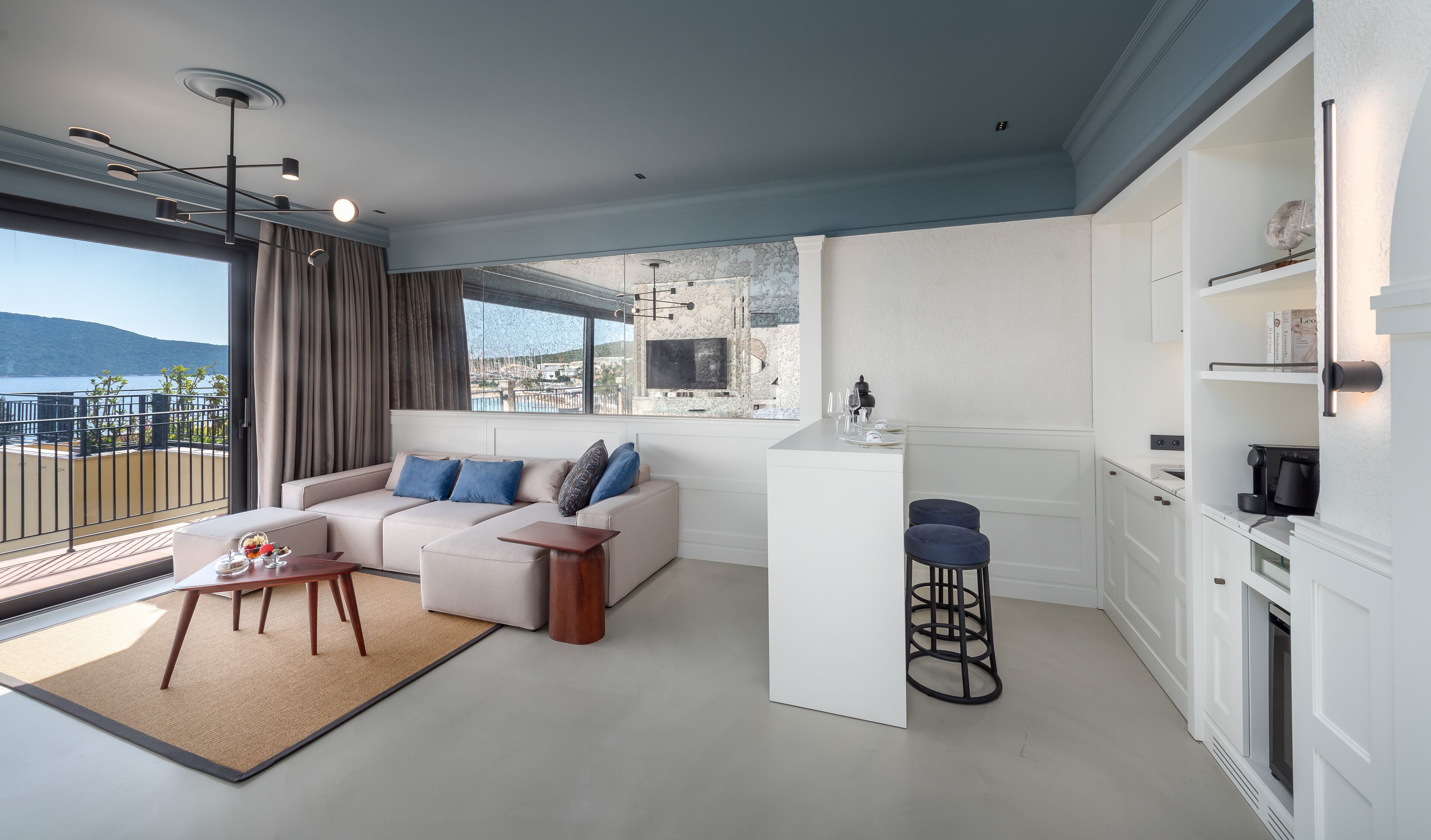 A modern living room with a sofa, coffee table, and a view of the sea.