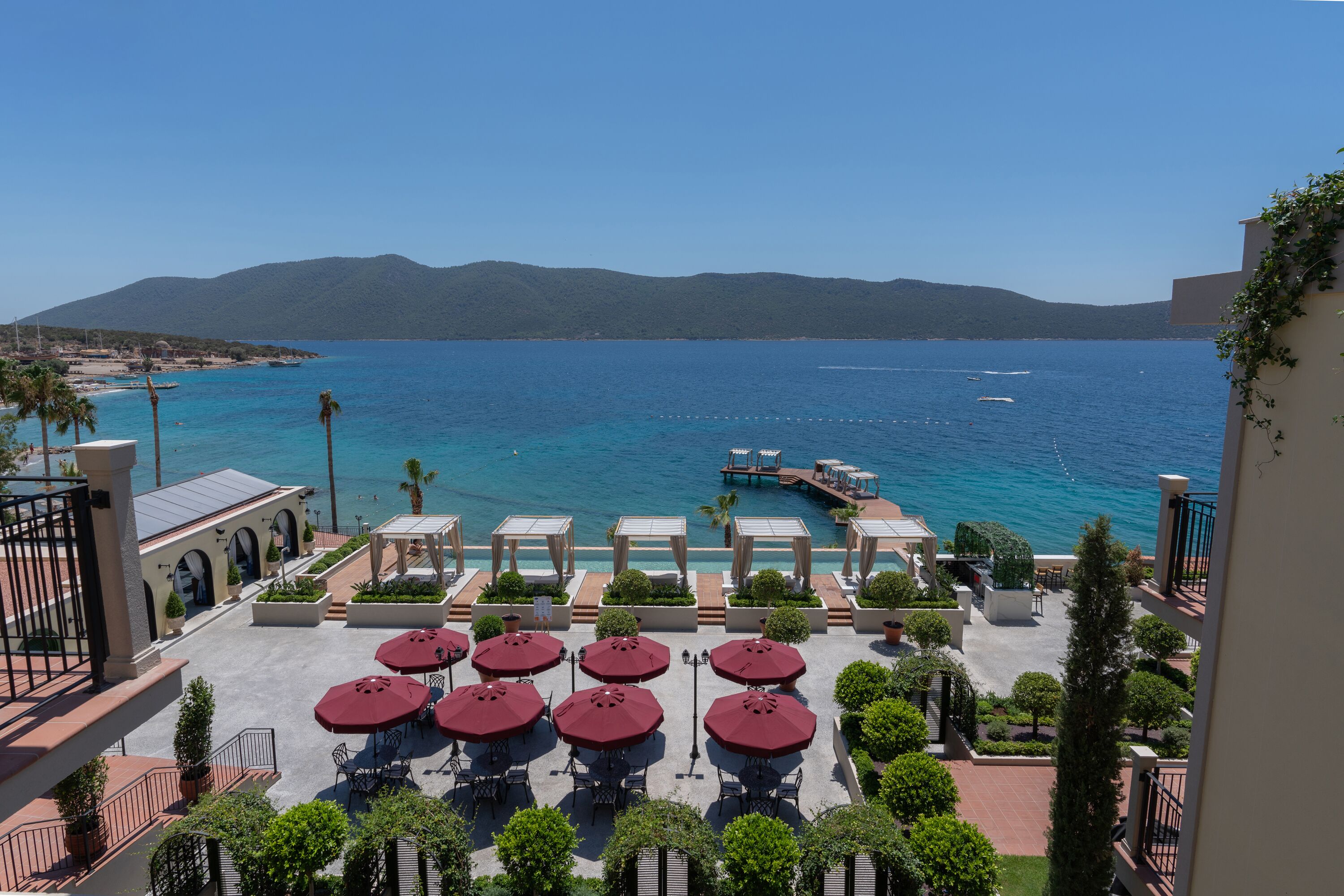 Un complexe hôtelier doté d’une terrasse, d’une piscine et offrant une vue sur la mer et les montagnes.