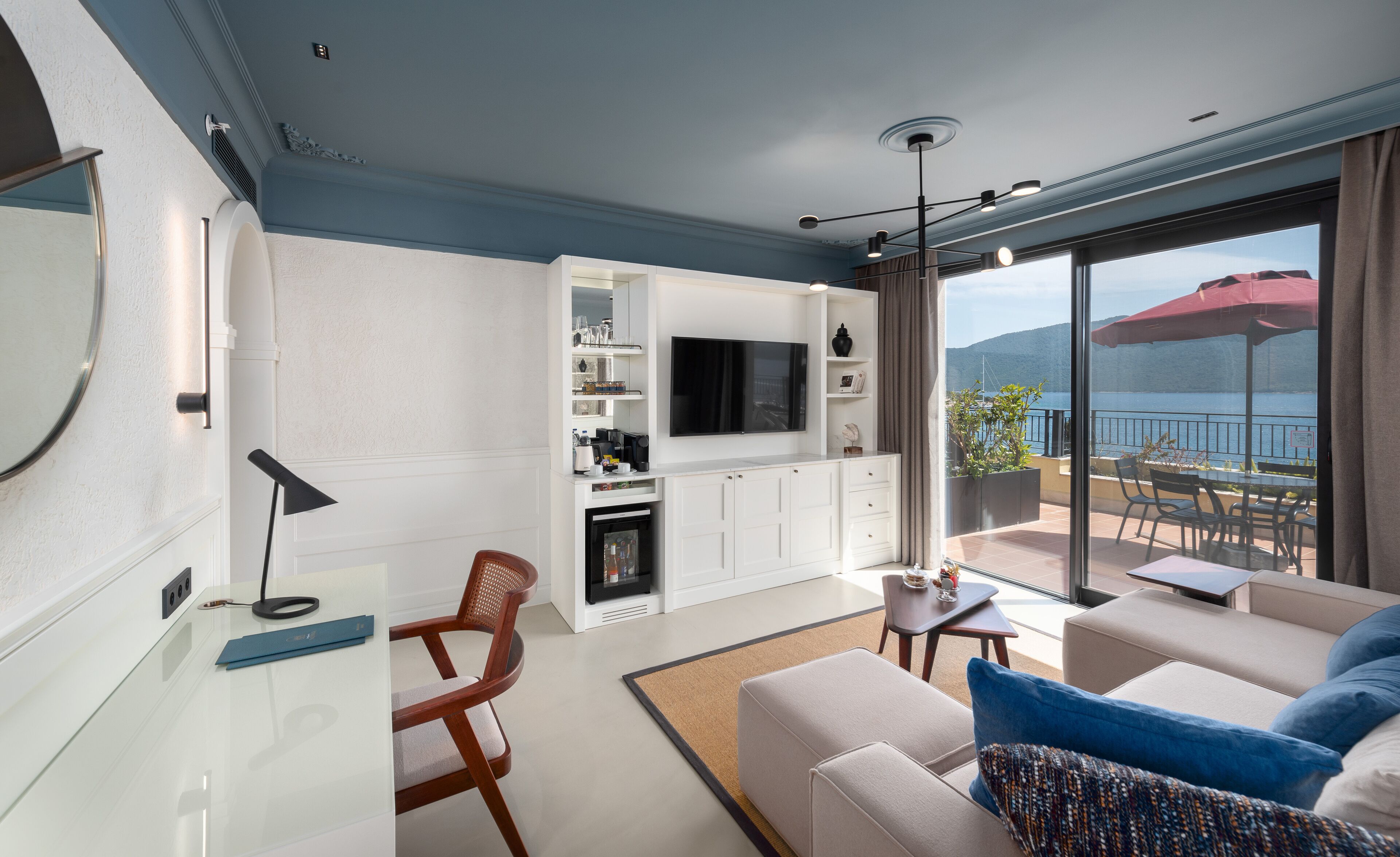 Una sala moderna con televisor, asientos y un balcón con vistas.