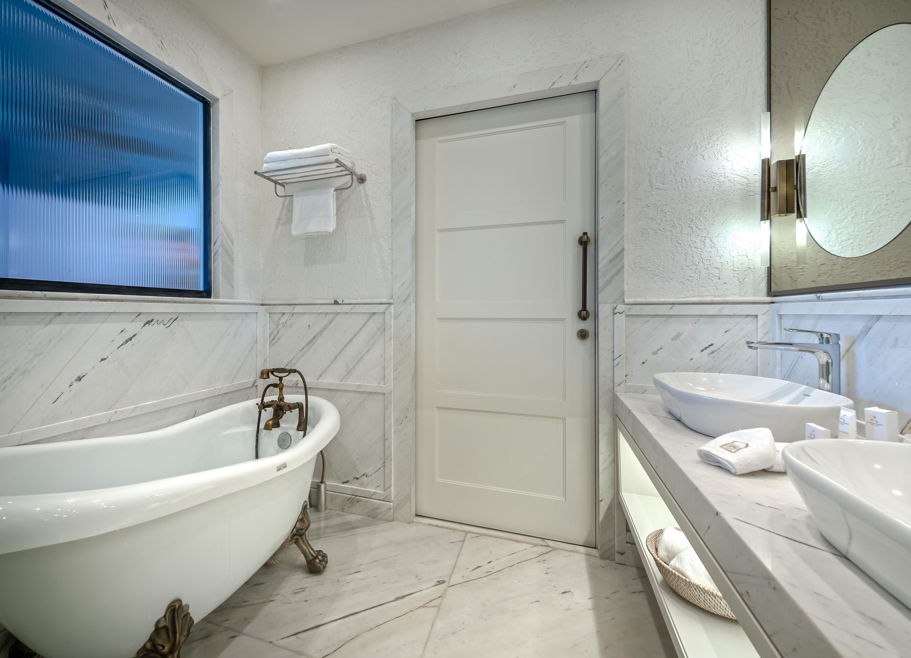 A bathroom with a freestanding bathtub, a sink, a mirror, and a door.