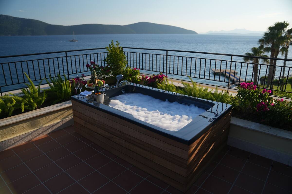 A hot tub on a balcony with a view of the sea and mountains.