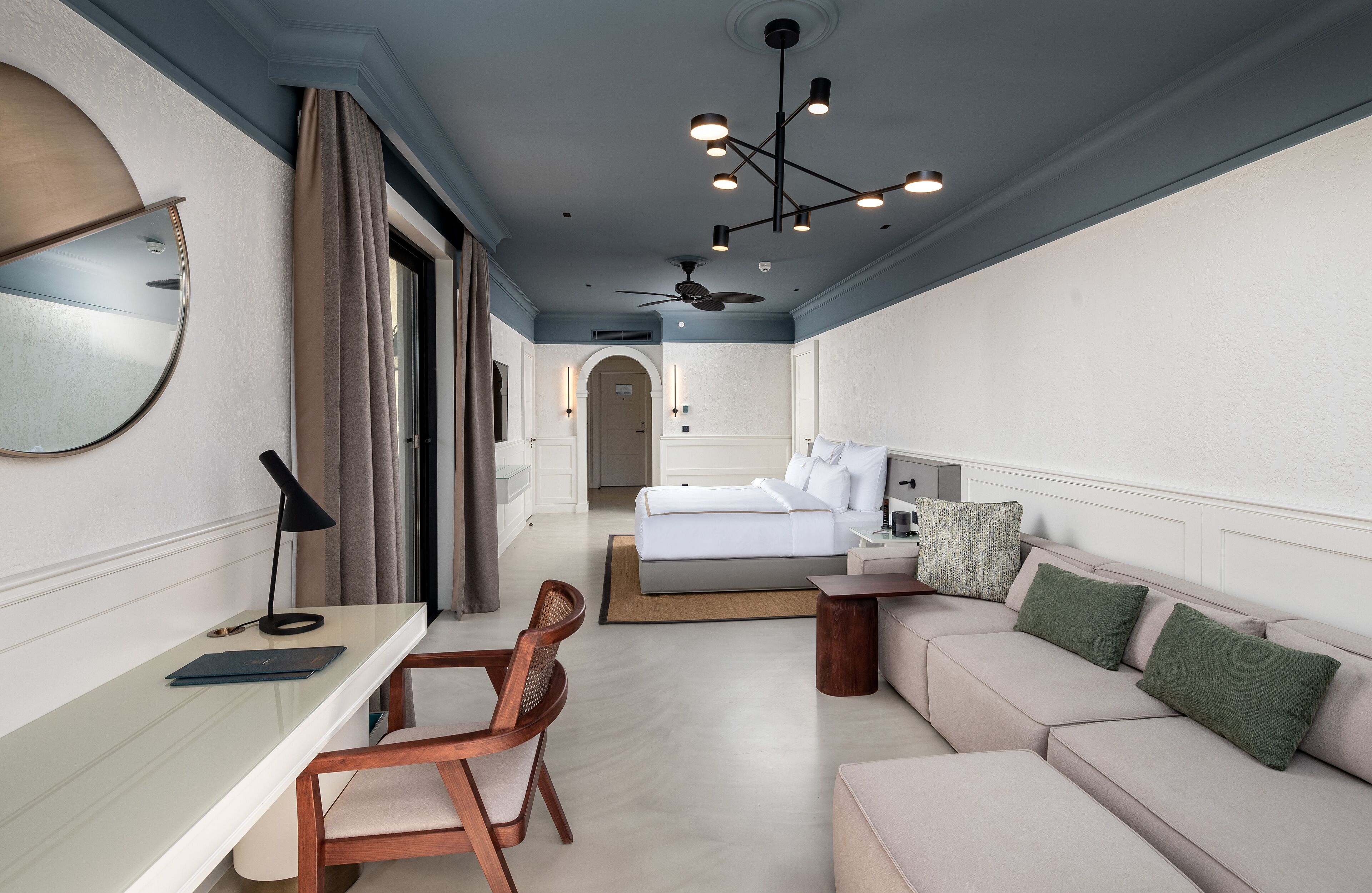 Una habitación de hotel moderna con cama, sofá, escritorio y silla.