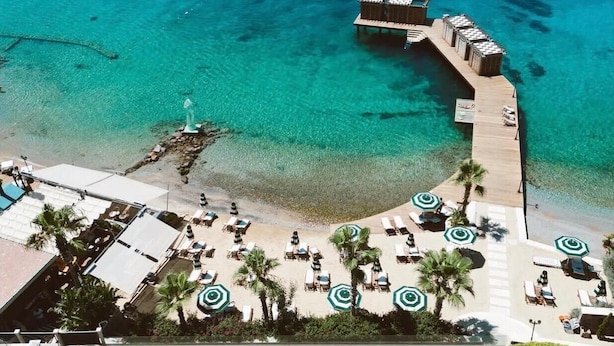 An aerial view of a resort with a pool, beach area, and a pier extending into the ocean. - Casa Nonna Bodrum - Adult Only (Bodrum)