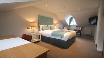 A modern bedroom with a large bed, a desk, and a TV.