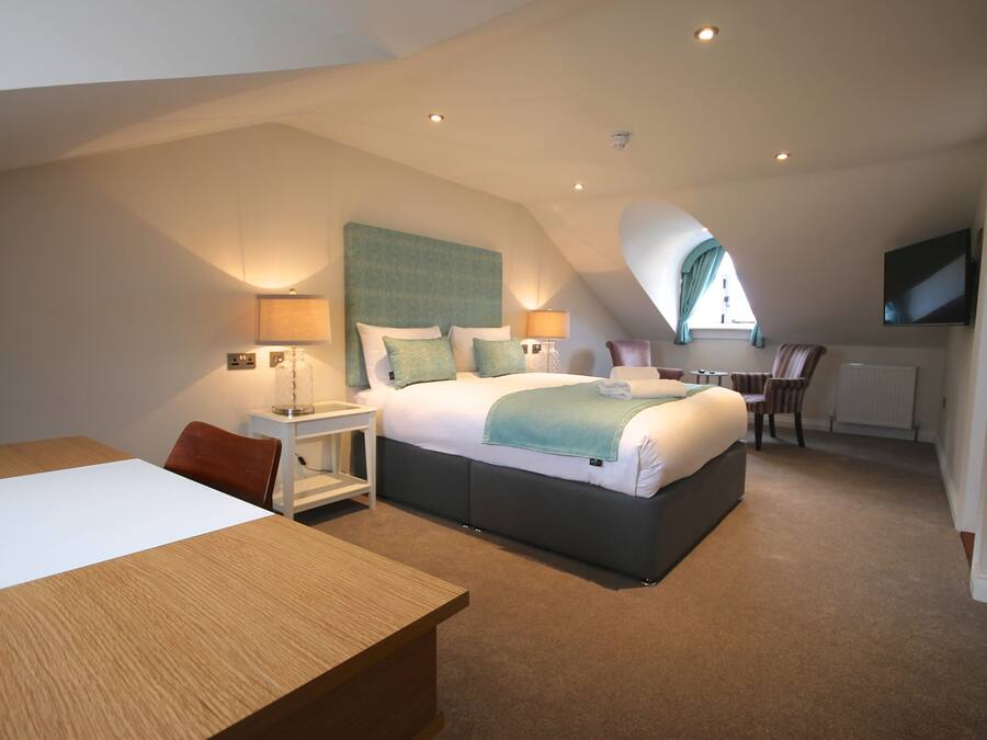 A modern bedroom with a large bed, a desk, and a TV.