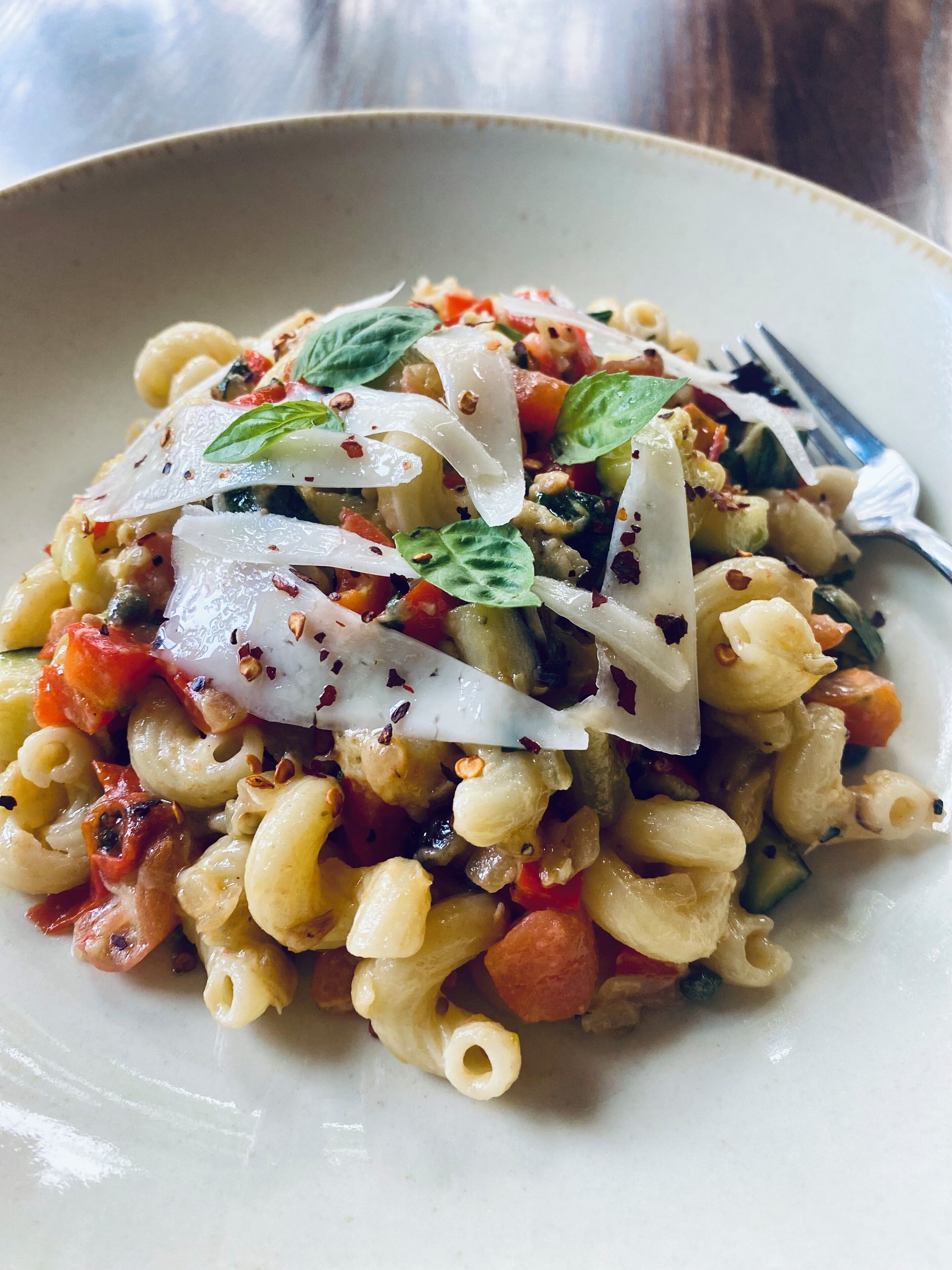 A plate of pasta with vegetables and herbs.