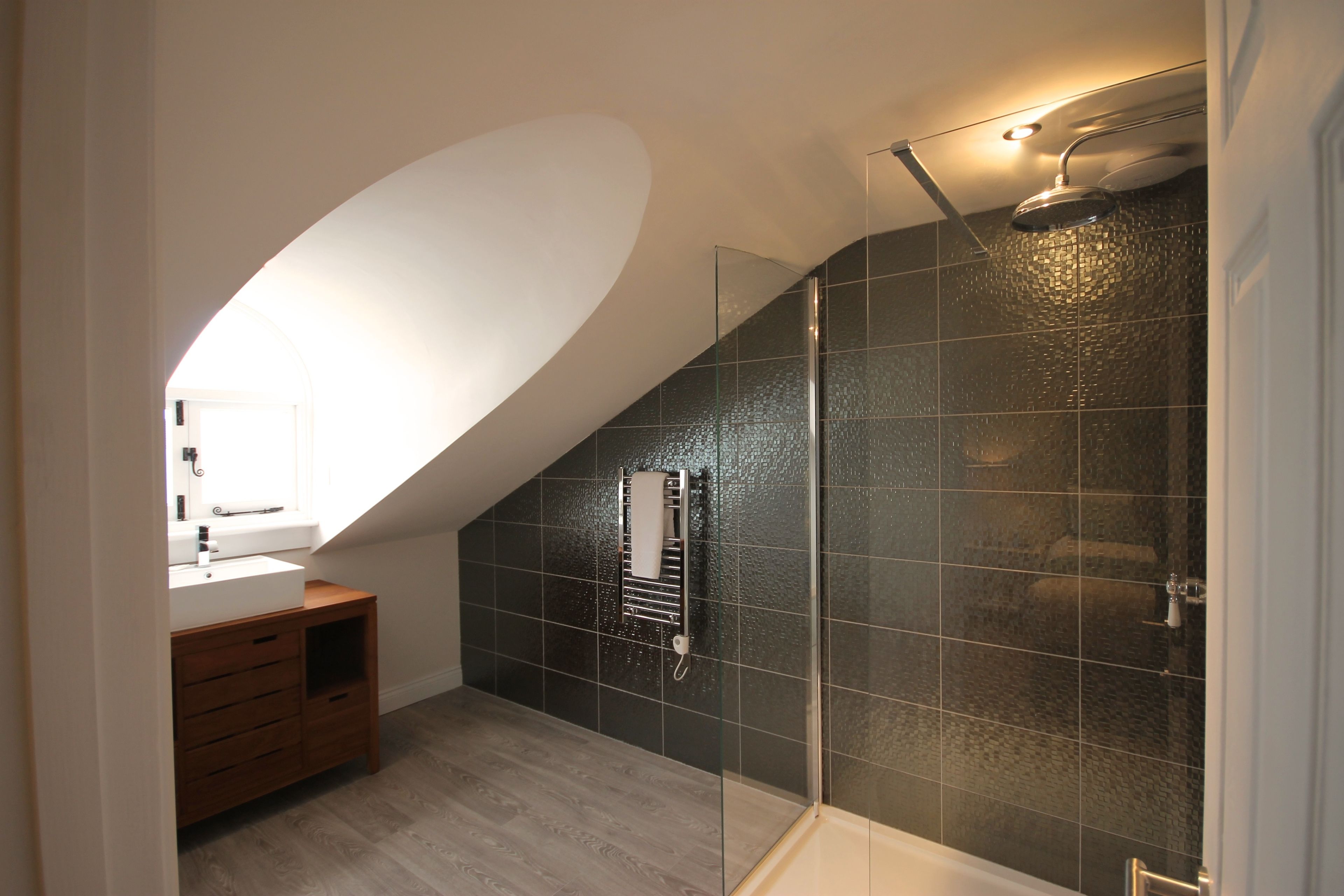 A modern bathroom with a glass-enclosed shower, a wooden vanity, and a white sink.