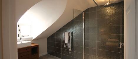 A modern bathroom with a glass-enclosed shower, a wooden vanity, and a white sink.