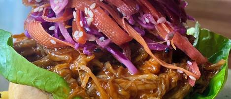 A sandwich with pulled pork, red cabbage, and lettuce, accompanied by French fries.