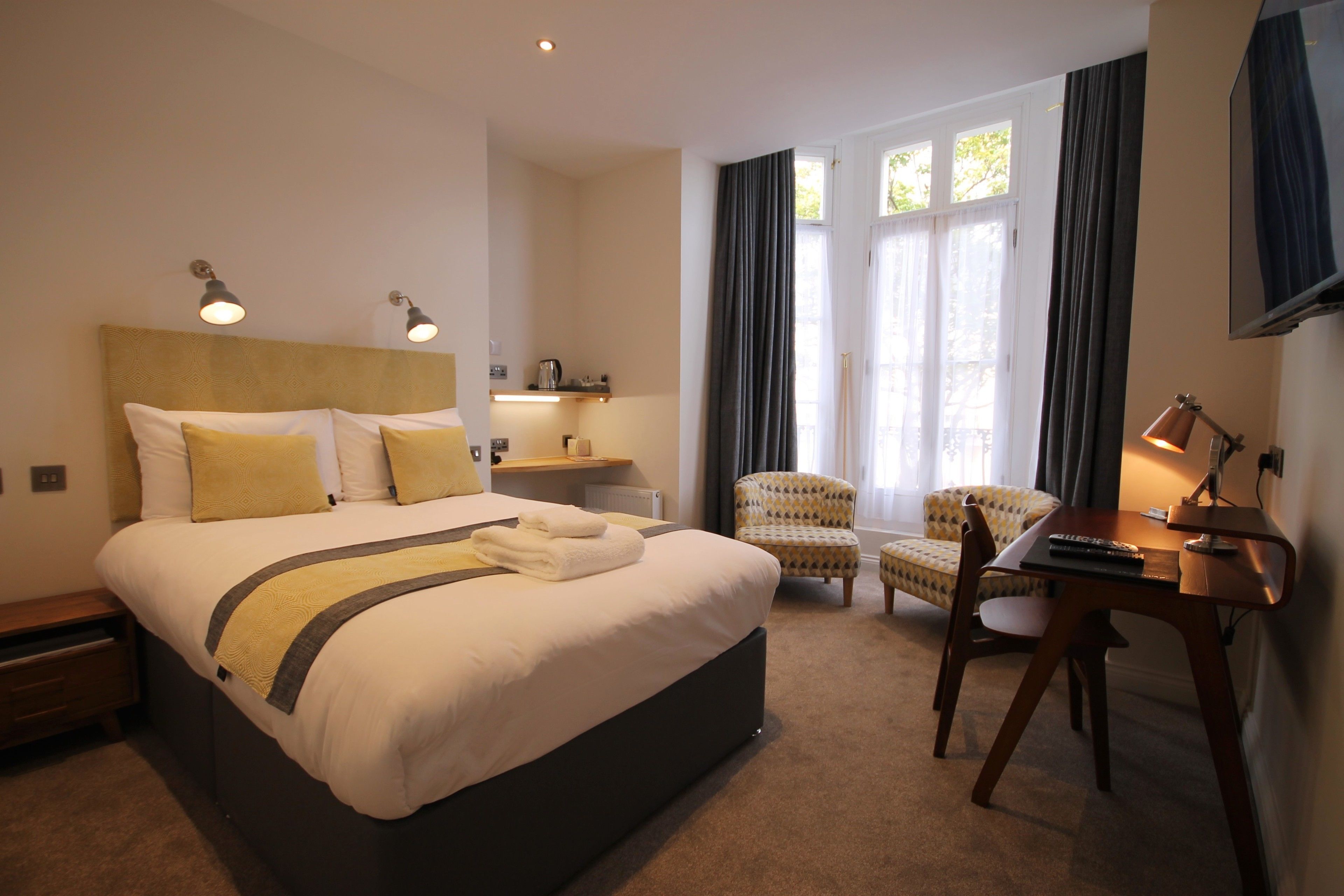 Une chambre d’hôtel avec un grand lit, un bureau, une chaise et un téléviseur.