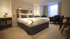 Une chambre d’hôtel moderne, dotée d’un grand lit, de tables de chevet, d’un bureau et d’une chaise.