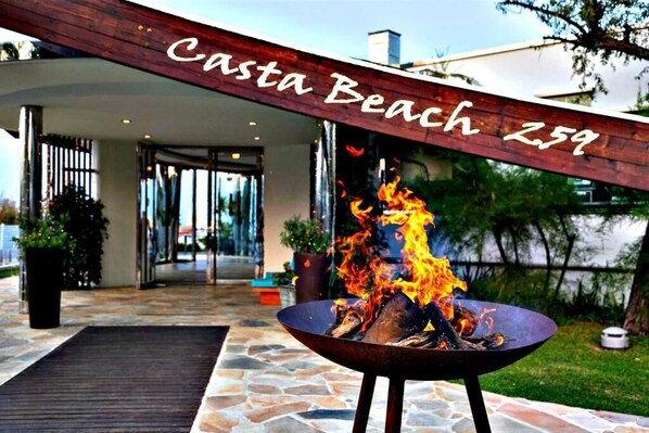 A fire pit with flames in front of a building labeled "Casta Beach Z59."