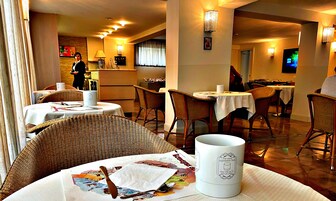Un comedor con sillas de mimbre, mesas redondas y mantel blanco.