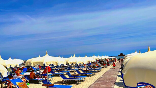 A beach with rows of sun loungers and white umbrellas. - Hotel Ambra (Cervia)