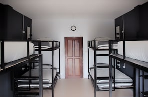 A dormitory room with bunk beds, a wooden door, and a wall clock. - Asia Blue The Tavern Hacienda - Hostel (Ko Pha-ngan)
