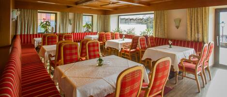A restaurant with wooden ceilings, red and white checkered chairs, and tables set for dining.