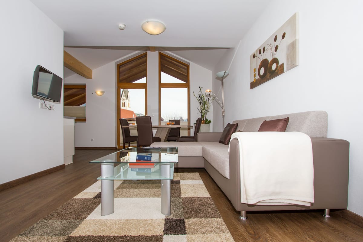 A modern living room with a glass coffee table, a sofa, and a dining area with a view.