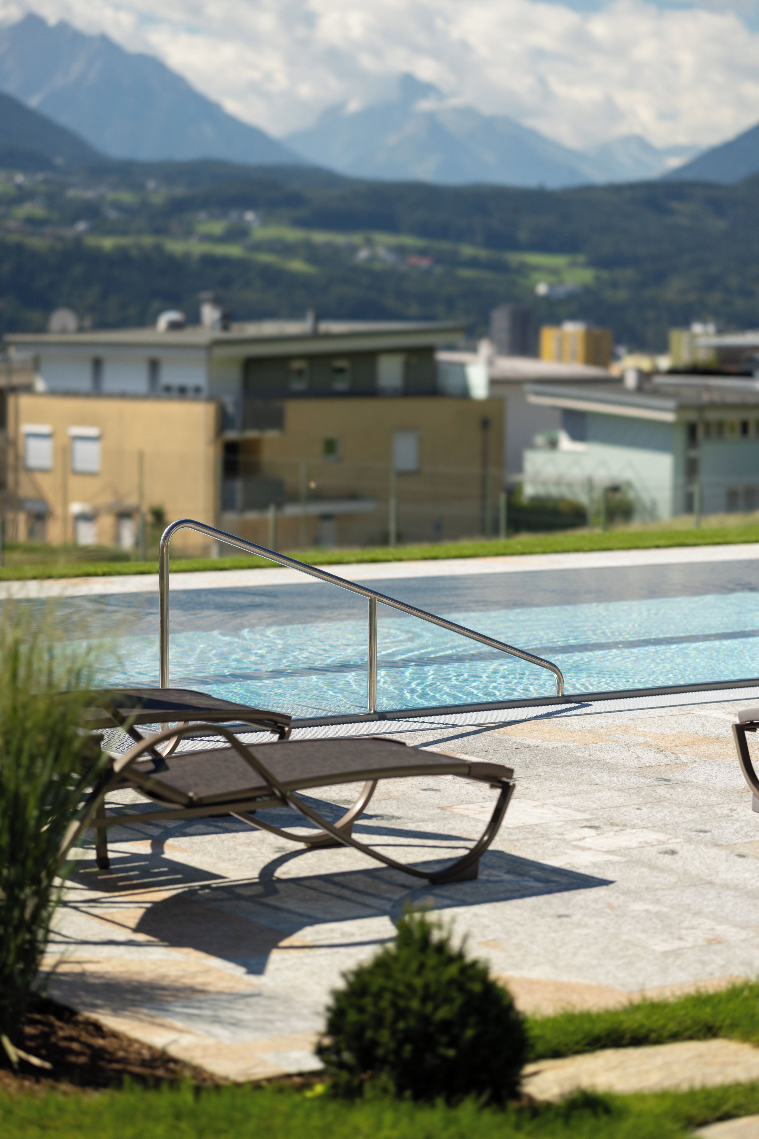 A swimming pool with lounge chairs and a view of mountains in the background.