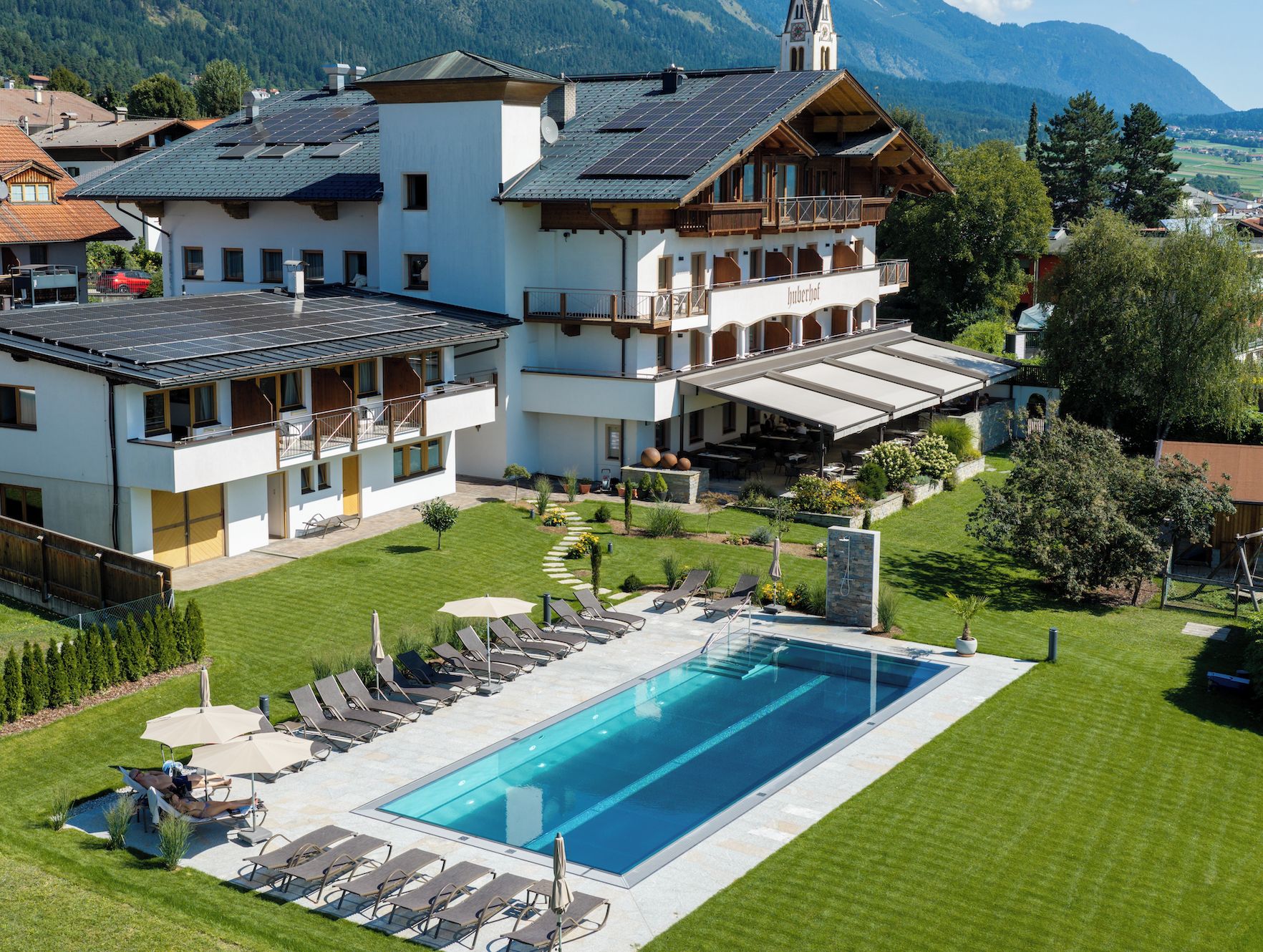 A large building with a swimming pool, outdoor seating, and a mountain backdrop.