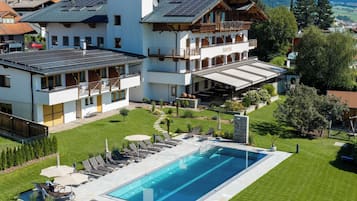 A large building with a swimming pool, outdoor seating, and a mountain backdrop.