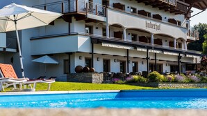 A hotel with a pool area, outdoor seating, and a two-story structure. - Hotel Huberhof (Rum)
