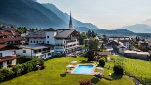 A large building with a swimming pool, surrounded by houses and mountains. - Hotel Huberhof (Rum)