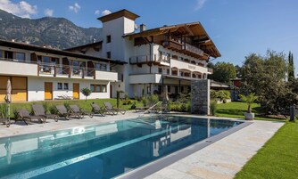 Un hotel con piscina, area salotto esterna e vista sulle montagne.