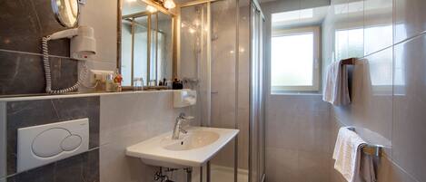 A modern bathroom with a glass-enclosed shower, a sink with a mirror, and a towel rack.