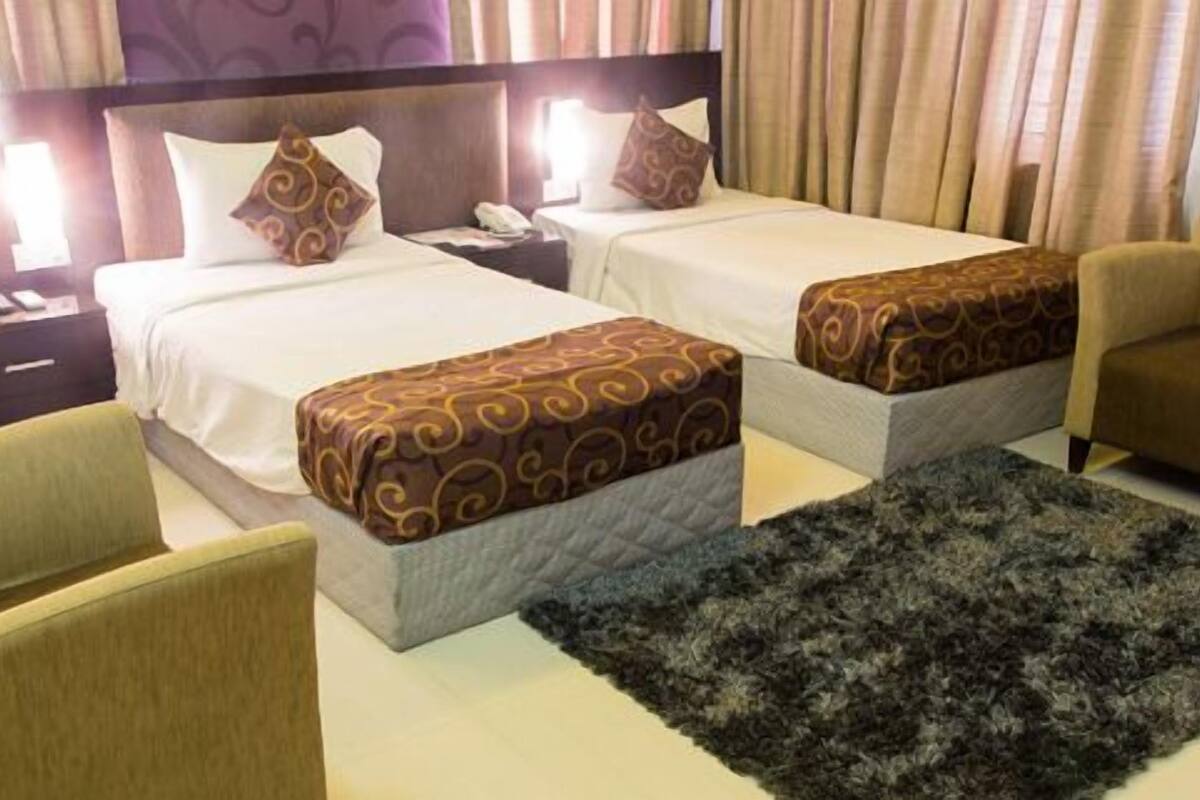 Une chambre d’hôtel avec deux lits, une table de chevet, une chaise et un tapis.