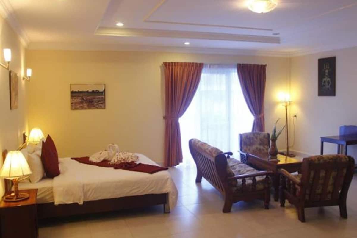 Een hotelkamer met een bed, een stoel, een bureau en een lamp.