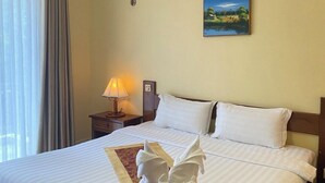 Een hotelkamer met een groot bed, een schilderij aan de muur, een lamp en een raam met gordijnen.