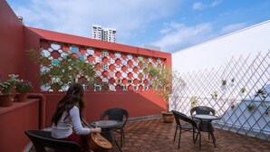Une terrasse sur le toit avec un mur rouge, des plantes en pot et des sièges d’extérieur.