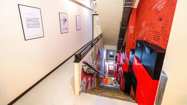 A staircase with a handrail, a red wall with graffiti, and framed documents on the wall. - Beds & Dreams Inn @ Clarke Quay (Singapore)
