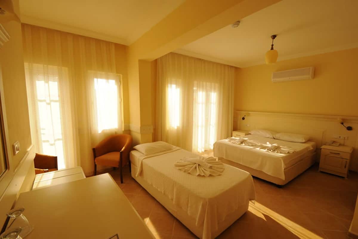 A hotel room with two beds, a desk, a chair, and a small table.