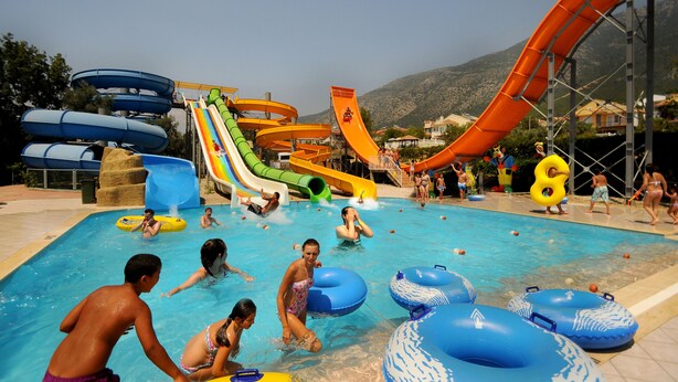 A water park with multiple slides and inflatable rings in a pool area. - The Grand Üçel Hotel (Fethiye)