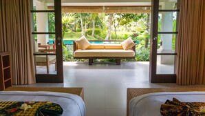 Habitación de hotel con cama, sofá y vistas a una piscina y zonas verdes.
