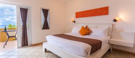 Habitación de hotel con una cama, una mesita de noche, una lámpara fijada a la pared y vistas al exterior.
