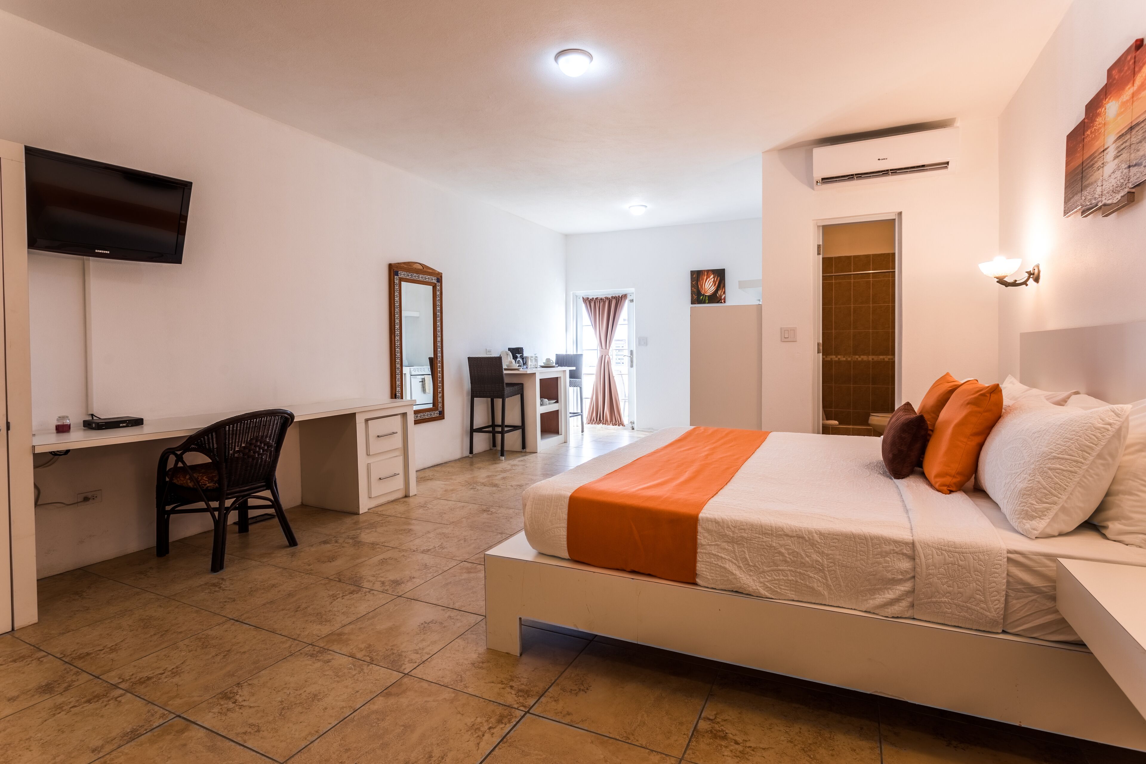 Un dormitorio con cama, escritorio, silla y televisor montado en la pared.