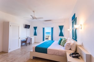 A bedroom with a bed, a desk, a chair, a phone, and a TV.