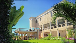 A two-story building with a flat roof, a balcony on the upper floor, and a well-maintained garden with various plants and flowers. - La Vue Boutique Inn (South Hill)