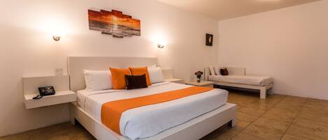 A modern hotel room with a large bed, a smaller bed, a nightstand with a phone, and a wall-mounted artwork.
