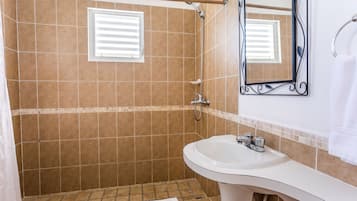 Un baño con ducha, lavamanos y espejo.