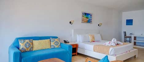 A room with a blue sofa, a bed, a small wooden table, and a wicker chair.