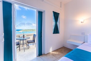 A room with a bed, a small table with chairs, a view of the sea, and a balcony with a table and chairs. - La Vue Boutique Inn (South Hill)