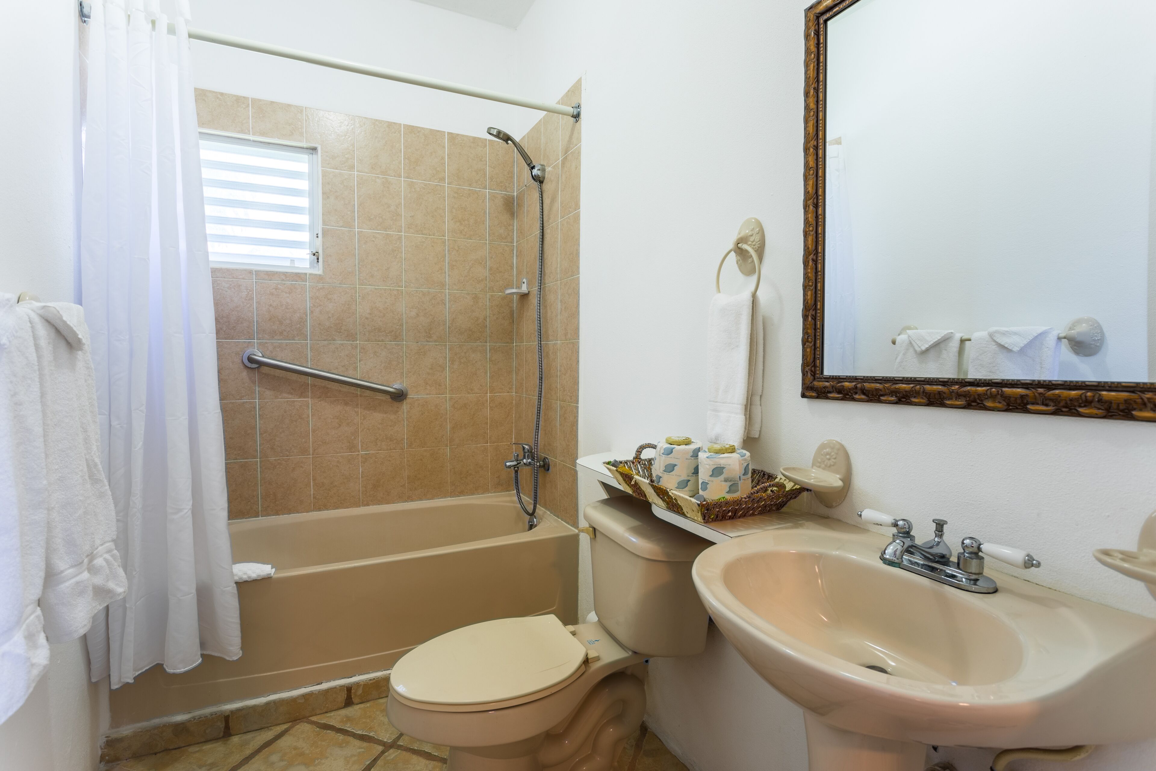 A bathroom with a bathtub, toilet, sink, and a mirror.