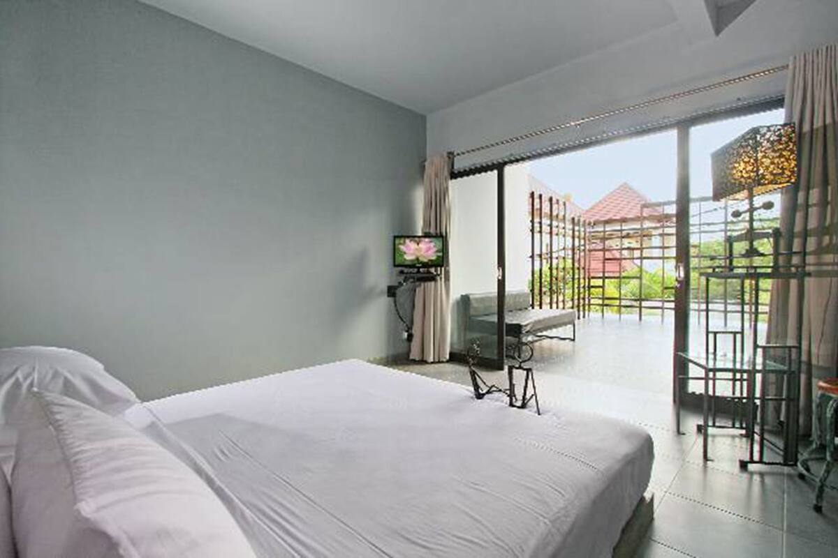 A hotel room with a bed, a TV, a desk, and a balcony with a view.